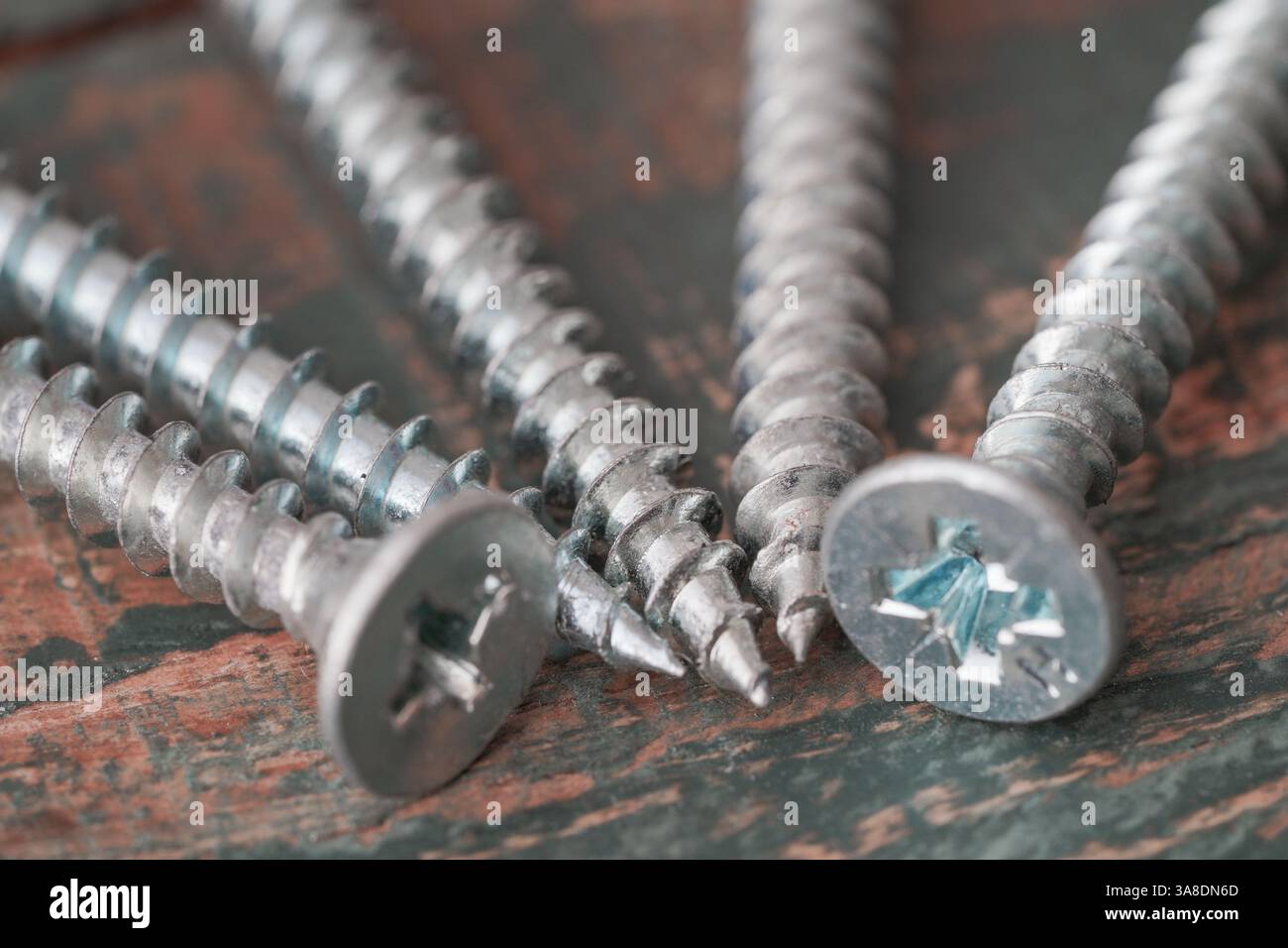 Primo piano di viti metalliche su una superficie rustica in legno, perfetto per progetti di costruzione, riparazione e miglioramento della casa. Foto Stock