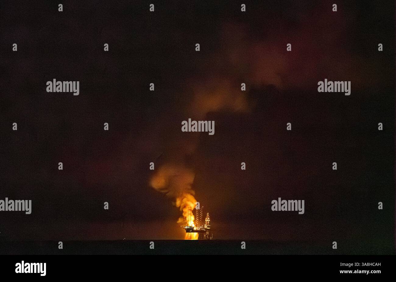 Doha, Qatar - 14 gennaio 2024, Vista panoramica della piattaforma petrolifera, che brucia gas naturale in eccesso, durante la produzione di petrolio, nel golfo persiano, di notte, Doha, Foto Stock