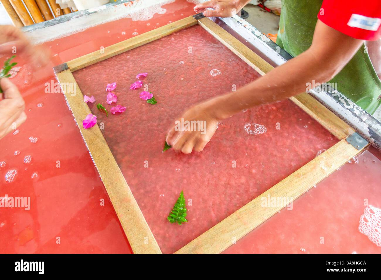 Un uomo filippino produce carta fatta a mano all'interno di un negozio di artigianato a Kalibo, nelle Filippine, lavorando con cura con la polpa e gli utensili tradizionali Foto Stock