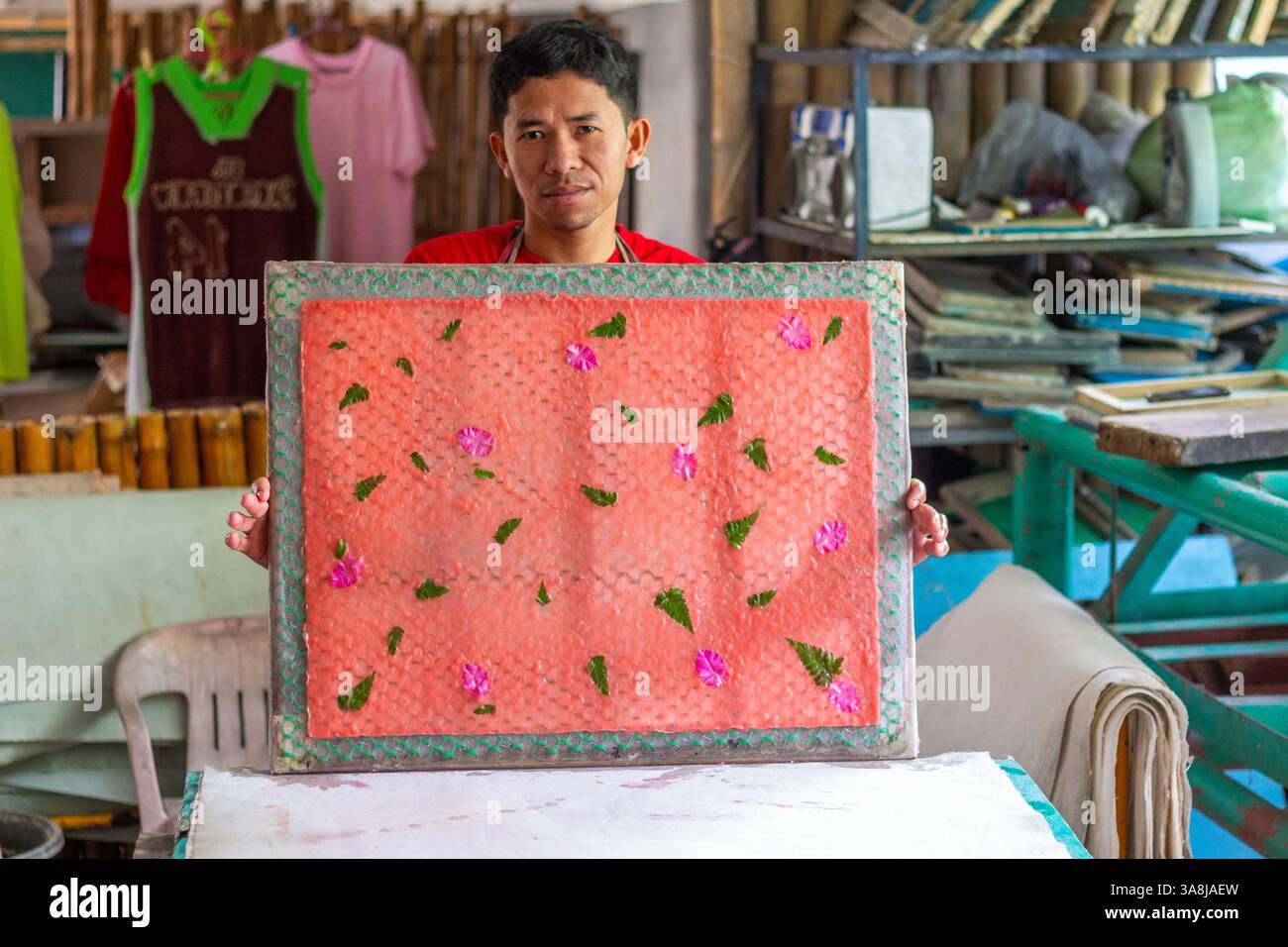 Un uomo filippino produce carta fatta a mano all'interno di un negozio di artigianato a Kalibo, nelle Filippine, lavorando con cura con la polpa e gli utensili tradizionali Foto Stock