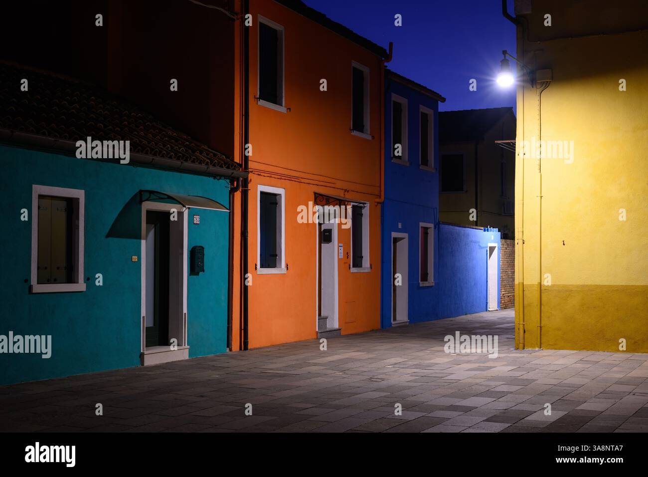 Case colorate di Burano illuminate di notte, case tradizionali nella laguna di Venezia dipinte con colori brillanti Foto Stock