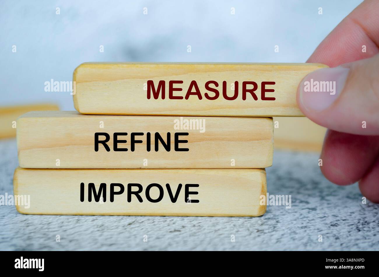 Misurare, perfezionare e migliorare il testo sui blocchi di legno. Concetto di miglioramento continuo. Foto Stock