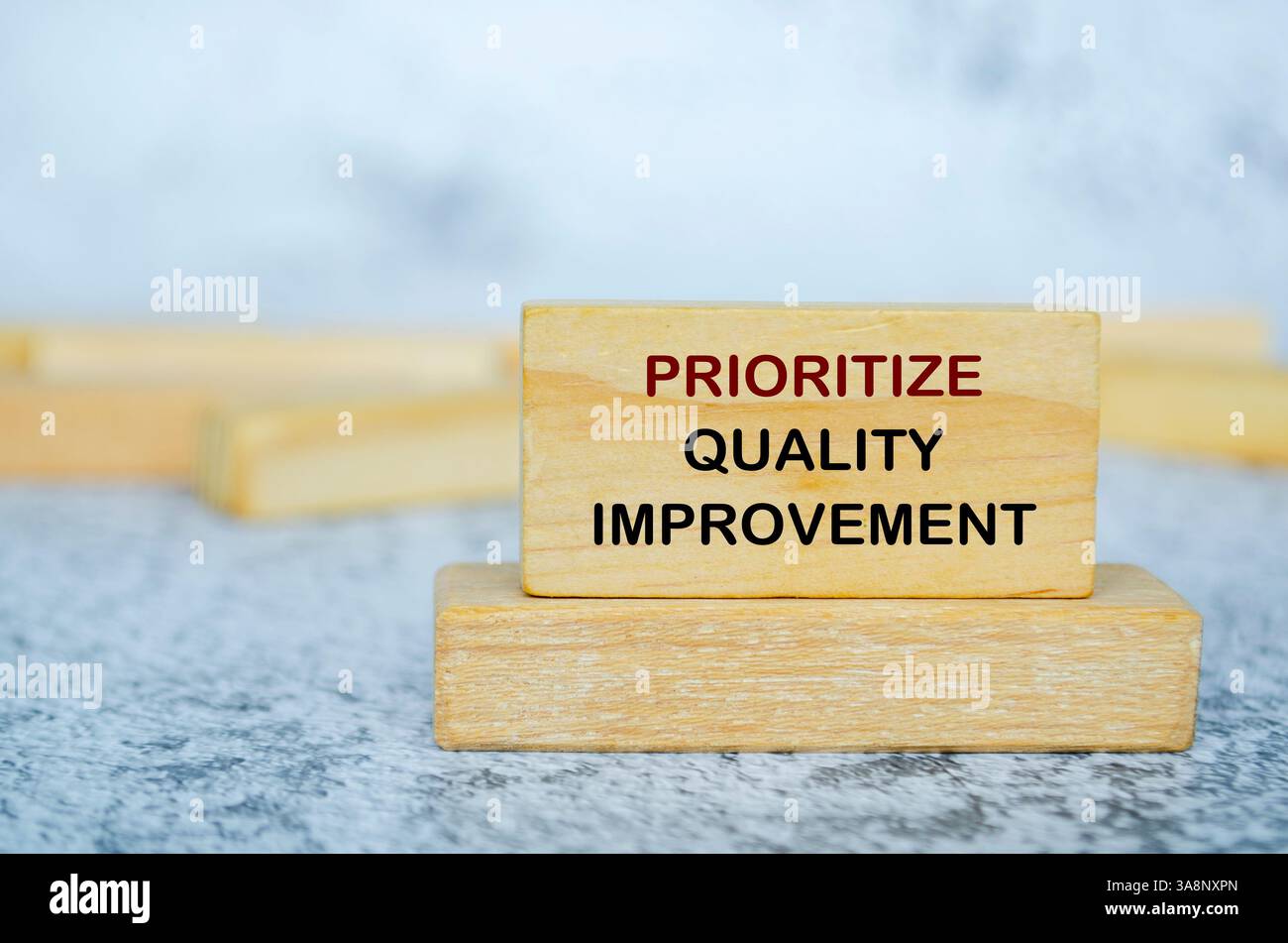 Dare priorità al testo di miglioramento della qualità sui blocchi di legno. Concetto di miglioramento continuo. Foto Stock