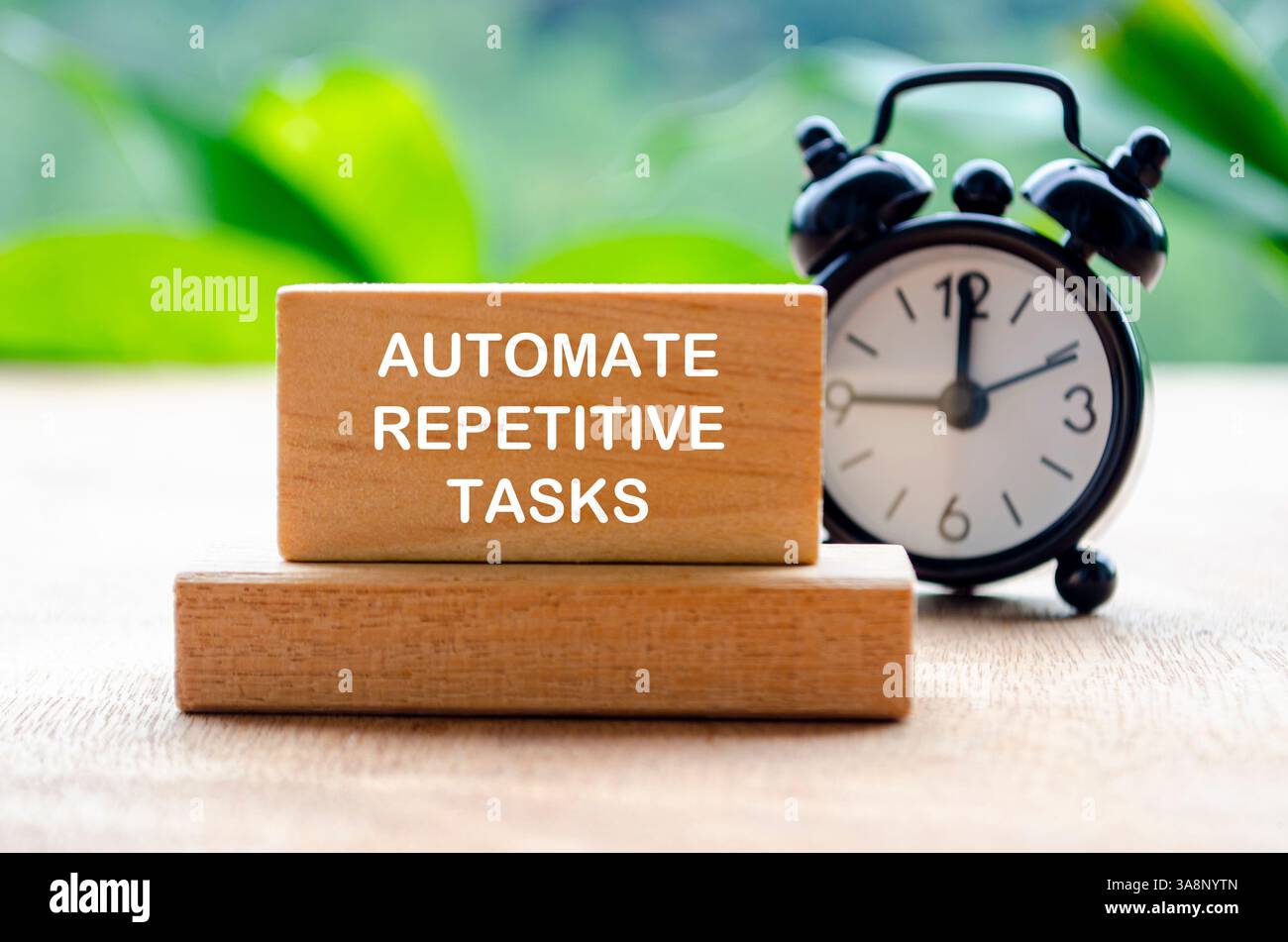 Automatizza il testo delle attività ripetitive su blocchi di legno con la sveglia nera sfocata. Foto Stock