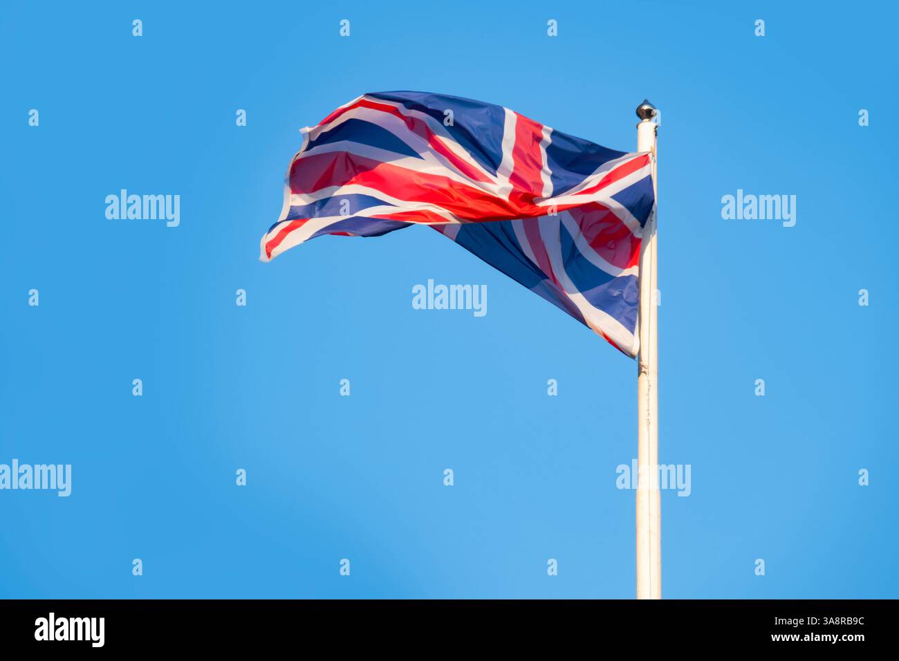 Bandiera del Regno Unito immersa nella storia, ondate contro il cielo azzurro, lo spirito duraturo e la ricca eredità del Regno Unito, Union Jack Foto Stock