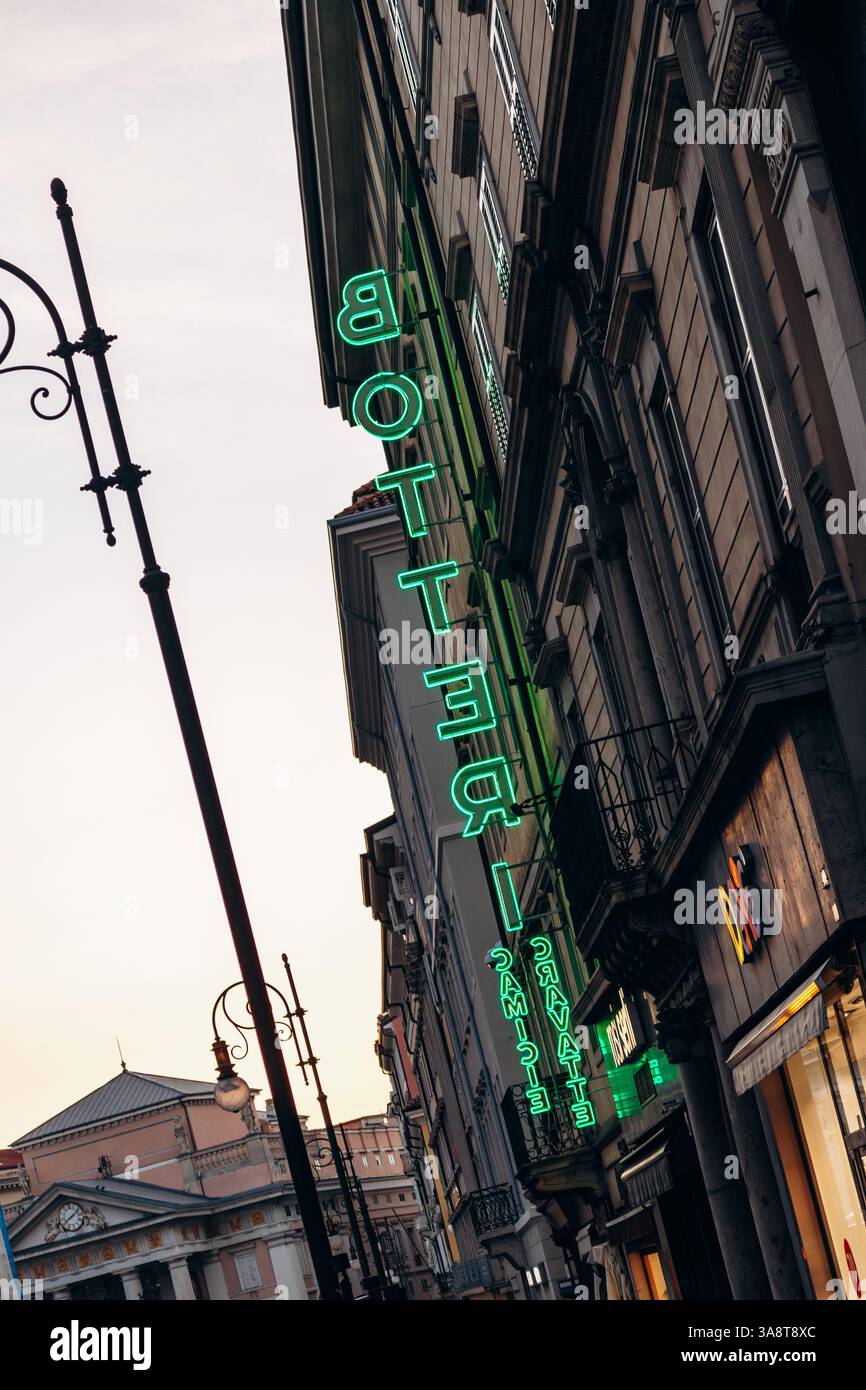 Trieste, Italia - 18 agosto 2024: L'insegna al neon illuminata, che proietta un vibrante bagliore sulla facciata dell'edificio nel cuore di Trieste. Foto Stock