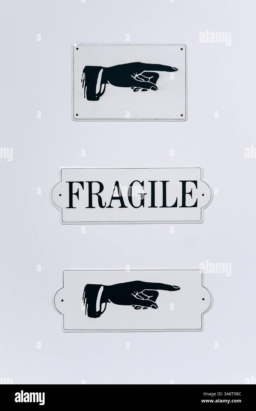 Una serie di insegne vintage: Due mani puntanti e un cartello di avvertimento "FRAGILE". Foto Stock