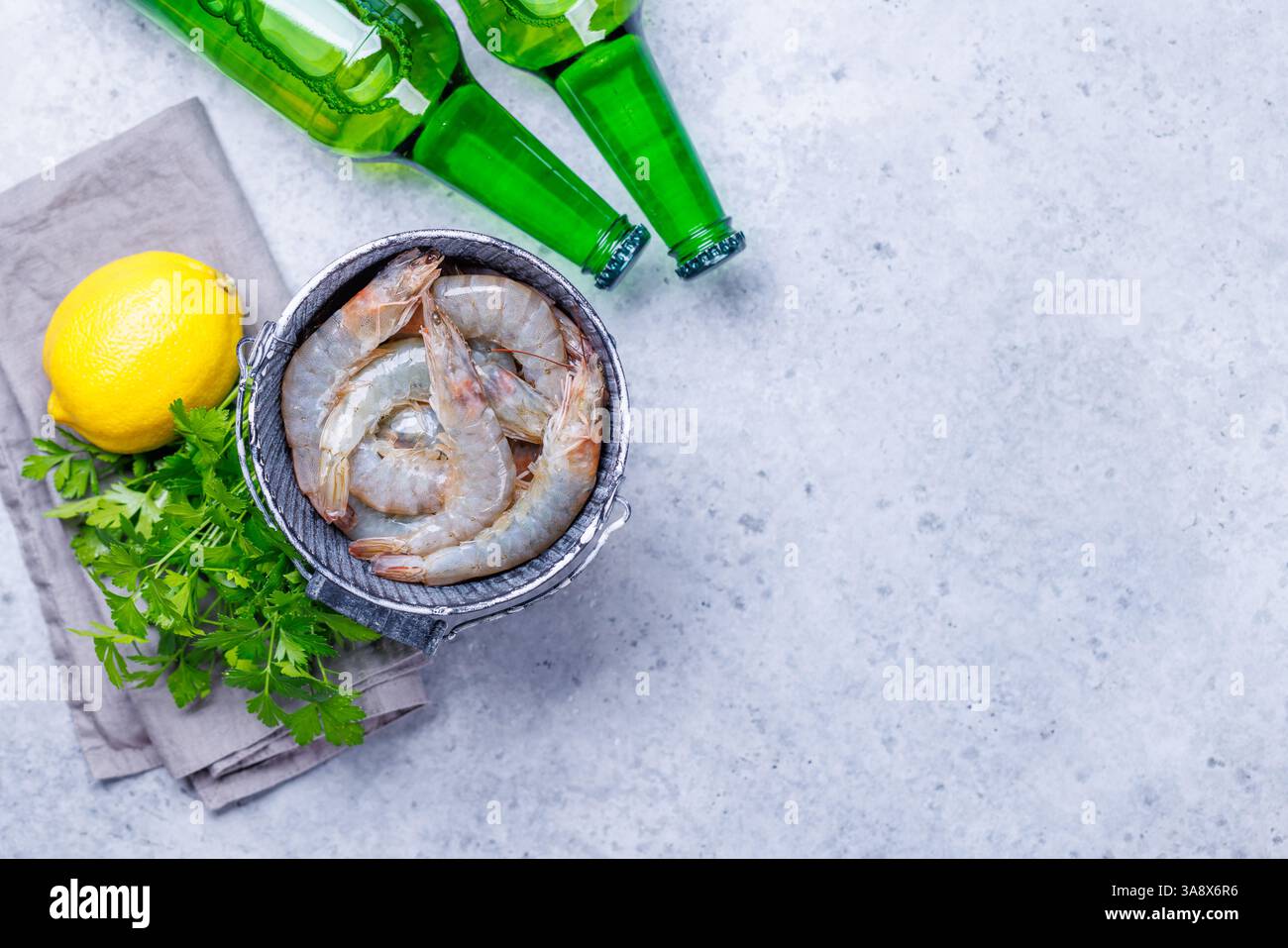 Gamberetti crudi freschi, accompagnati da rametti di prezzemolo fresco e limone succoso, pronti per la cottura. I colori vivaci degli ingredienti creano un aspetto visivo Foto Stock