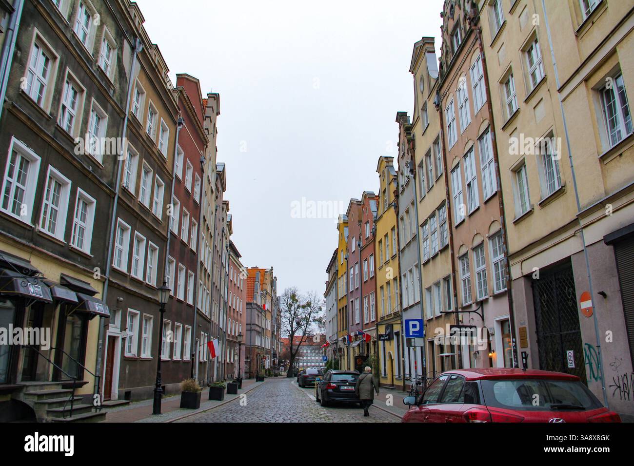 Danzica, Polonia - 11.11.2024: Una tranquilla strada residenziale a Gdańsk durante l'inverno, che ospita case cittadine colorate. Foto Stock