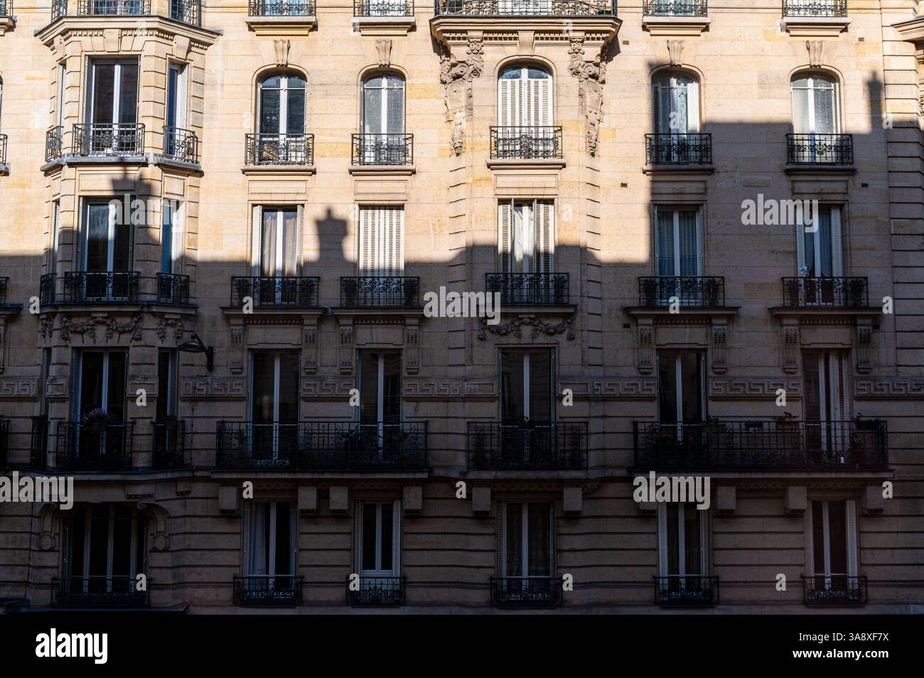 Facciata tipica di stile Haussmann di un vecchio edificio a Parigi, in Francia, con una grande ombra su di esso Foto Stock