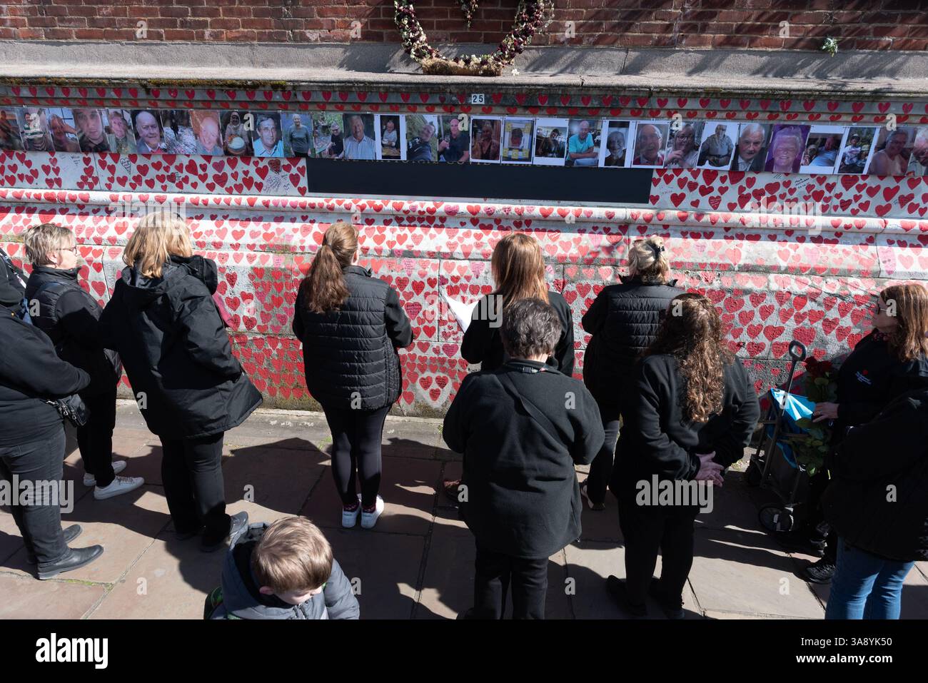 Londra, Regno Unito. 29 marzo 2025. Le famiglie e i parenti in lutto celebrano il quarto anniversario della creazione del National Covid Memorial Wall sull'Albert Embankment, proprio dall'altra parte del fiume rispetto al Parlamento. Il tributo non ufficiale si estende per 500 metri con un cuore rosso dipinto a mano raffigurante ciascuna delle oltre 240.000 vittime della pandemia di coronavirus nel Regno Unito. Centinaia di fotografie del defunto pendono lungo il muro che la processione commemorativa percorreva, leggendo tributi lungo il percorso. Crediti: Ron Fassbender/Alamy Live News Foto Stock