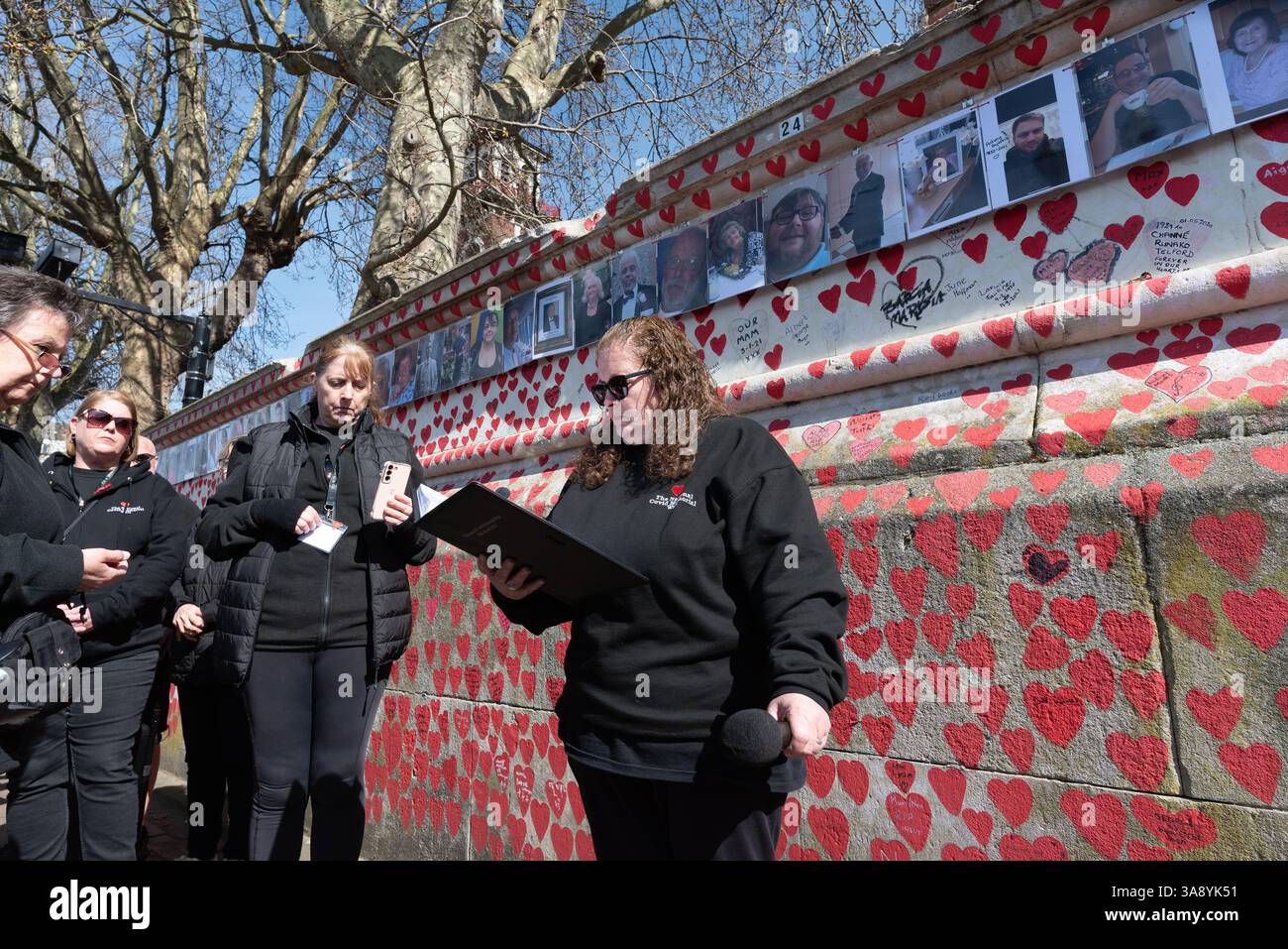 Londra, Regno Unito. 29 marzo 2025. Le famiglie e i parenti in lutto celebrano il quarto anniversario della creazione del National Covid Memorial Wall sull'Albert Embankment, proprio dall'altra parte del fiume rispetto al Parlamento. Il tributo non ufficiale si estende per 500 metri con un cuore rosso dipinto a mano raffigurante ciascuna delle oltre 240.000 vittime della pandemia di coronavirus nel Regno Unito. Centinaia di fotografie del defunto pendono lungo il muro che la processione commemorativa percorreva, leggendo tributi lungo il percorso. Crediti: Ron Fassbender/Alamy Live News Foto Stock