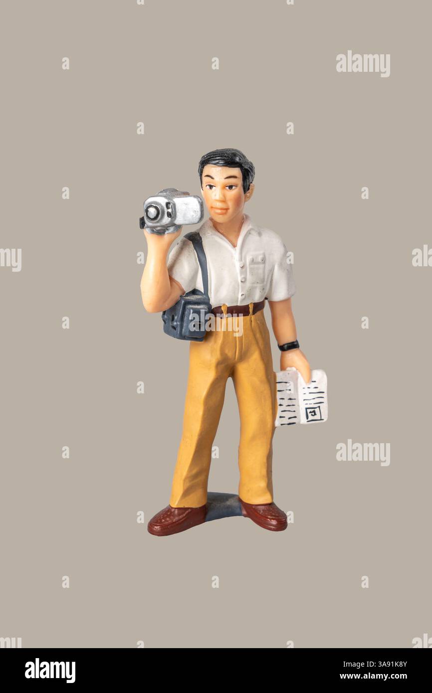 Un uomo ha una macchina fotografica e un giornale. Indossa una camicia bianca e pantaloni abbronzati Foto Stock