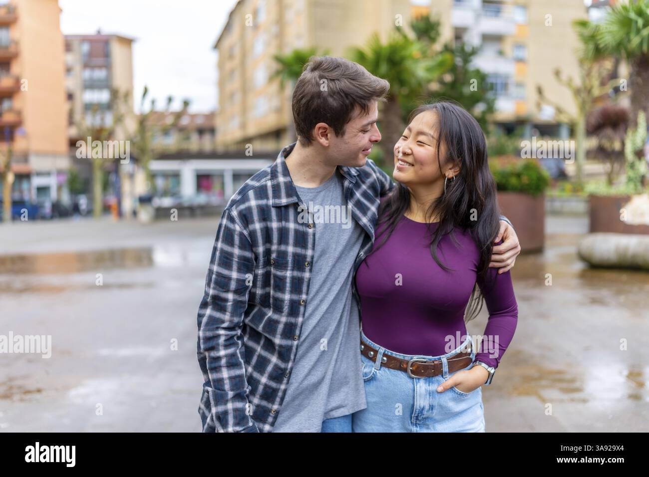Giovani coppie multietniche che condividono un momento di gioia all'aperto in un vivace ambiente urbano, che mette in mostra diversità e connessione nella vita di tutti i giorni Foto Stock