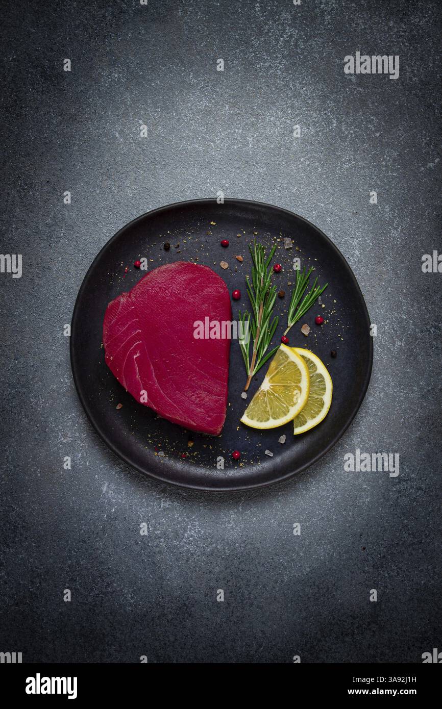 Filetto di tonno rosso fresco, per bistecche, crude, vista dall'alto, su un piatto nero, nessuno Foto Stock