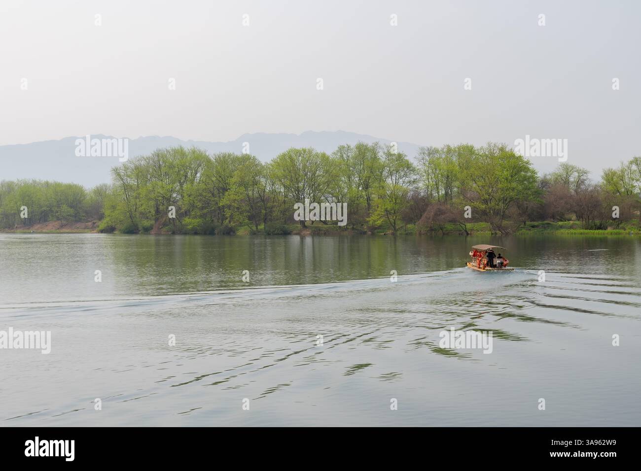 Barca cinese tradizionale che naviga attraverso il fiume Misty Mountain - viaggio tranquillo lungo il fiume in un paesaggio verde lussureggiante Foto Stock