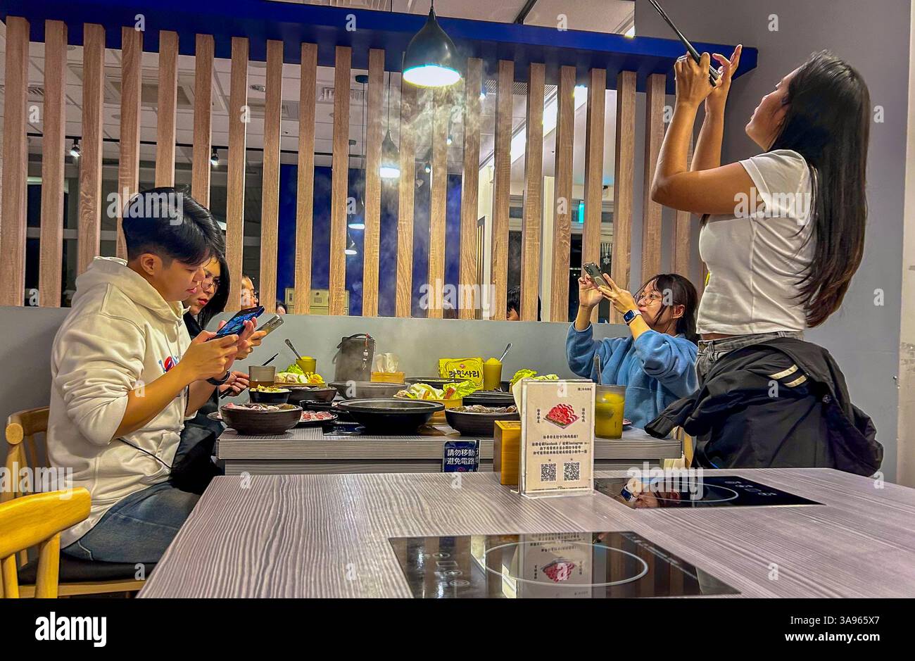 Yuchi, Taiwan, Lago Sun Moon, adolescenti di gruppo, taiwanesi, condividere i pasti, scattare foto, all'interno, ristorante taiwanese locale, tavolo, piatti caldi Foto Stock