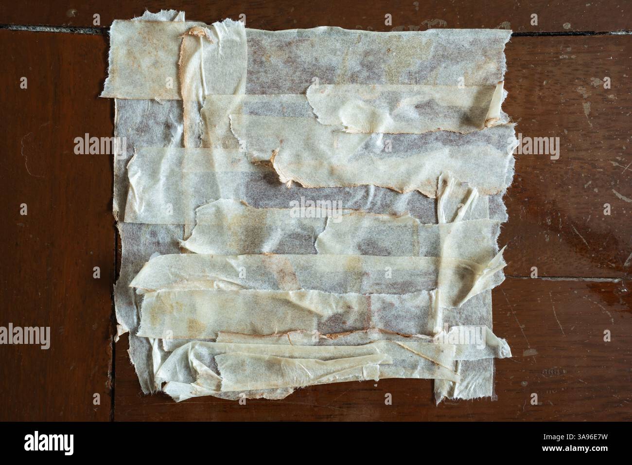 Forma quadrata realizzata con nastri di mascheratura usati su pavimento in legno Foto Stock