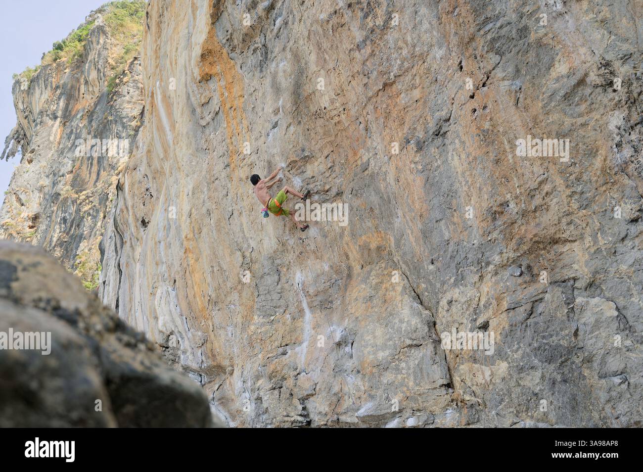 Un arrampicatore libero da solo sale su un torreggiante muro di pietra calcarea a Tonsai, una delle principali destinazioni di arrampicata al mondo Foto Stock