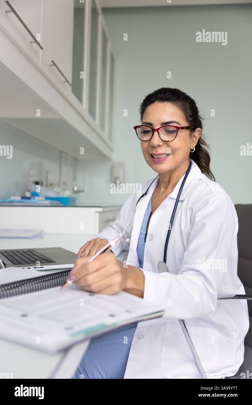 Medico professionista concentrato positivo donna che scrive note Foto Stock