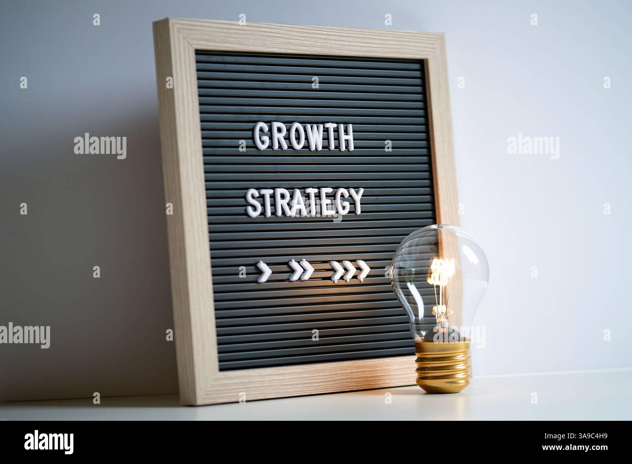 Un'immagine che mostra una lampadina accanto a una bacheca che mostra "strategia di crescita", sviluppo aziendale innovativo, progressi e concetti di pianificazione Foto Stock