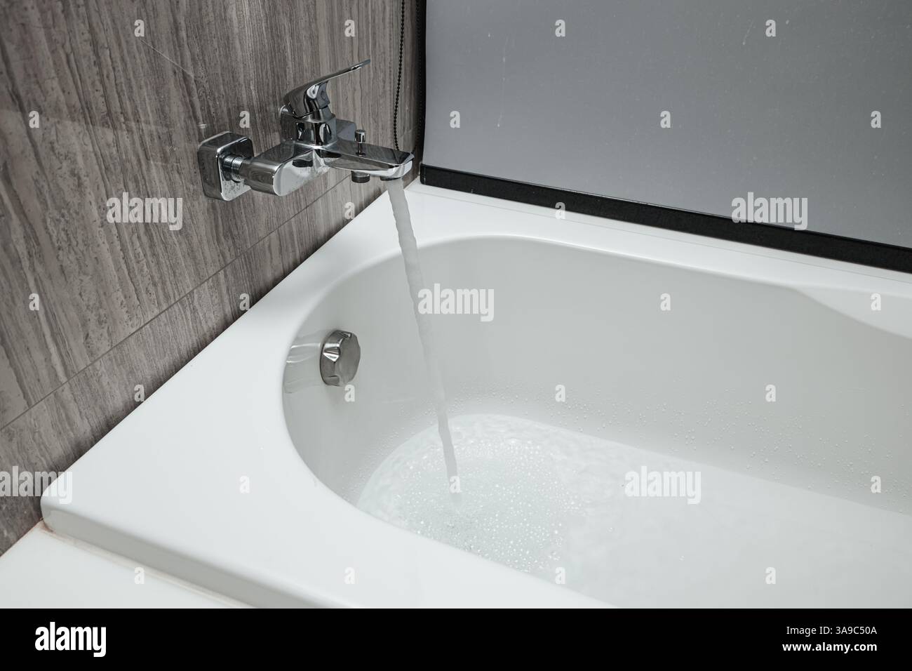 il rubinetto della doccia è acceso e la quantità di acqua fuoriesce dalla vasca da bagno. Foto Stock