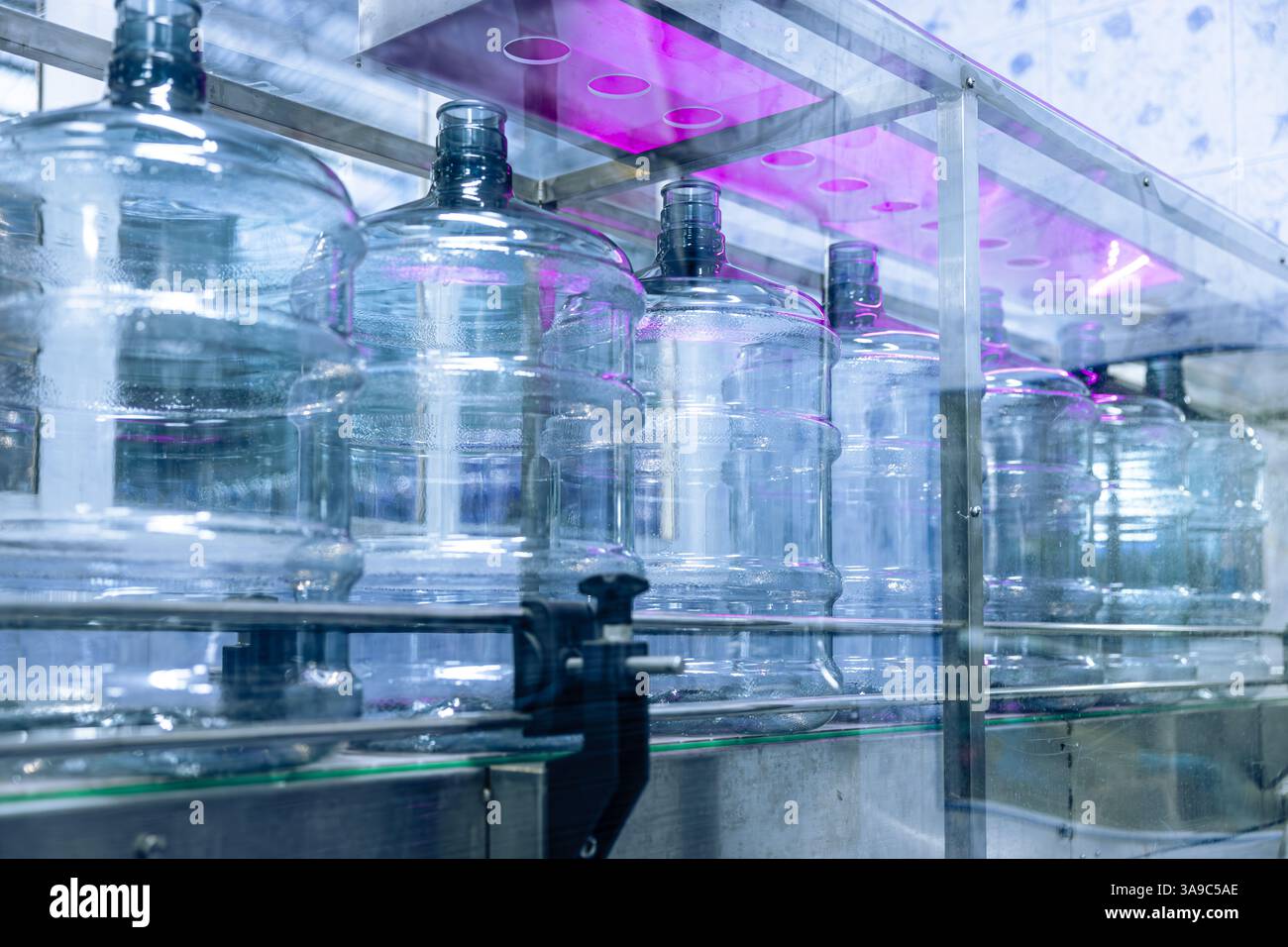 Sistema di disinfezione a luce UV, processo di sterilizzazione di bottiglie per la salute sicurezza igiene nella fabbrica dell'impianto di acqua potabile Foto Stock