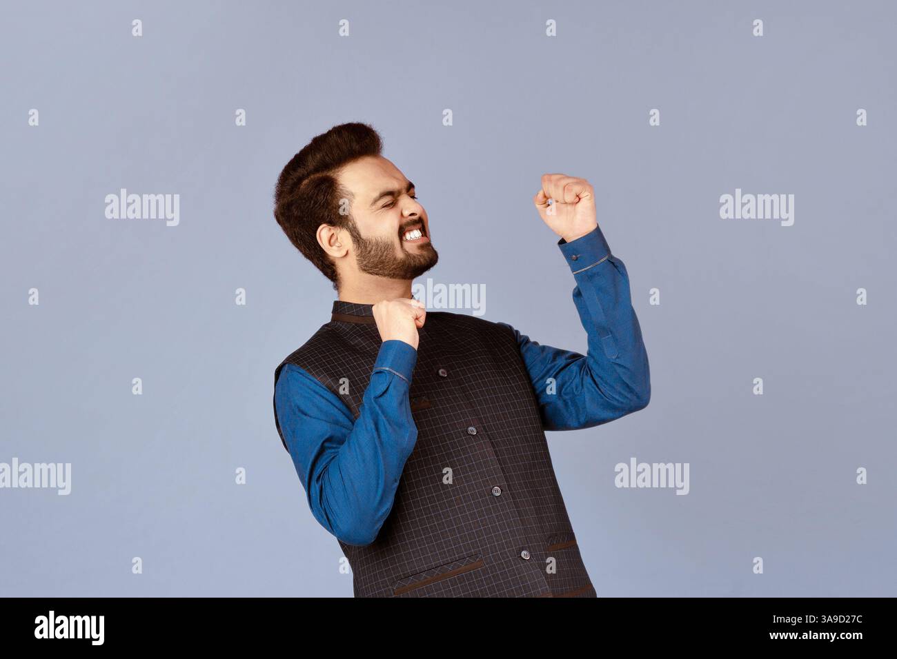 Concetto di successo. Eccitato ragazzo indiano sentirsi vittorioso e gesturing si su sfondo lilla Foto Stock