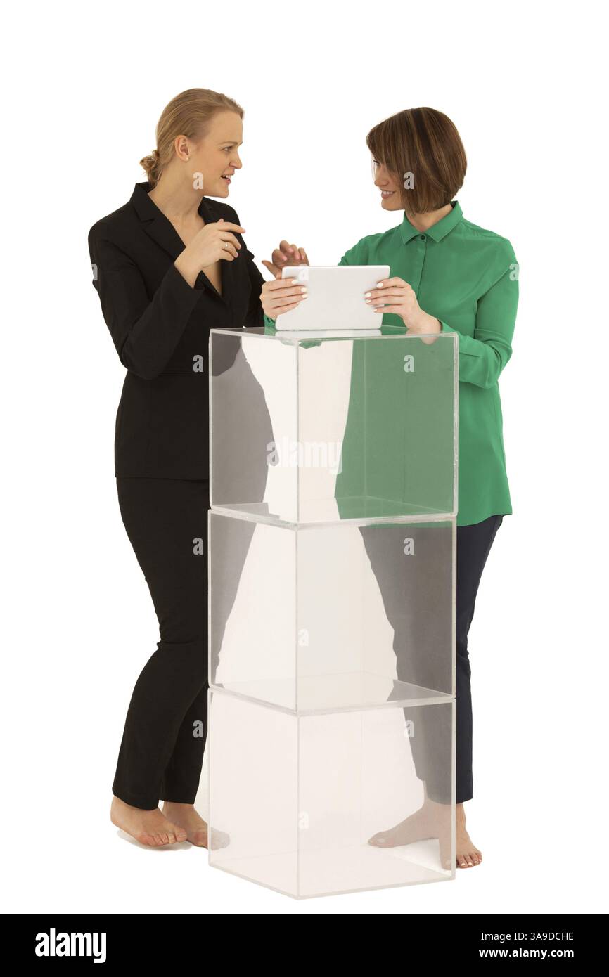 Due donne a piedi nudi cercando di ogni altro mentre si parla nei pressi di supporto costituito di cubetti di vetro. Uno di essi tenendo compressa. Sfondo bianco. Isolato Foto Stock