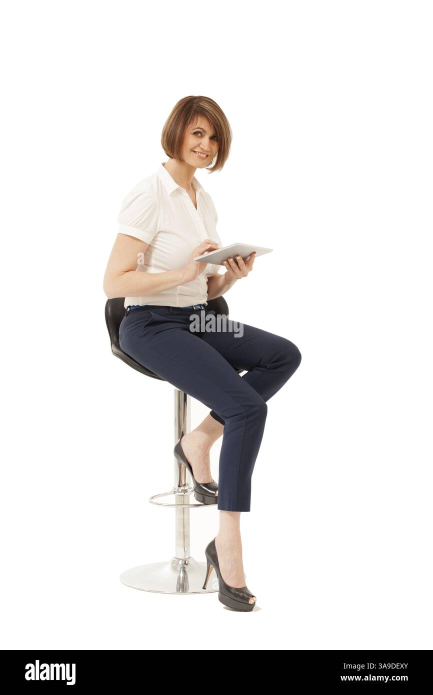 Elegante donna d'affari seduta su una sedia con imbottitura e che guarda la macchina fotografica. Isolata, ripresa in studio Foto Stock