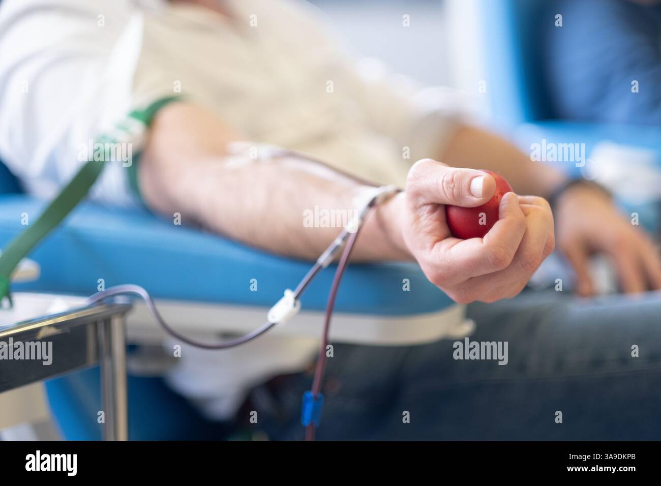 La mano di un donatore volontario pompa il sangue stringendo una sfera di gomma per migliorare il flusso del catetere. E' una banca per donazioni di sangue, e un volontario Foto Stock