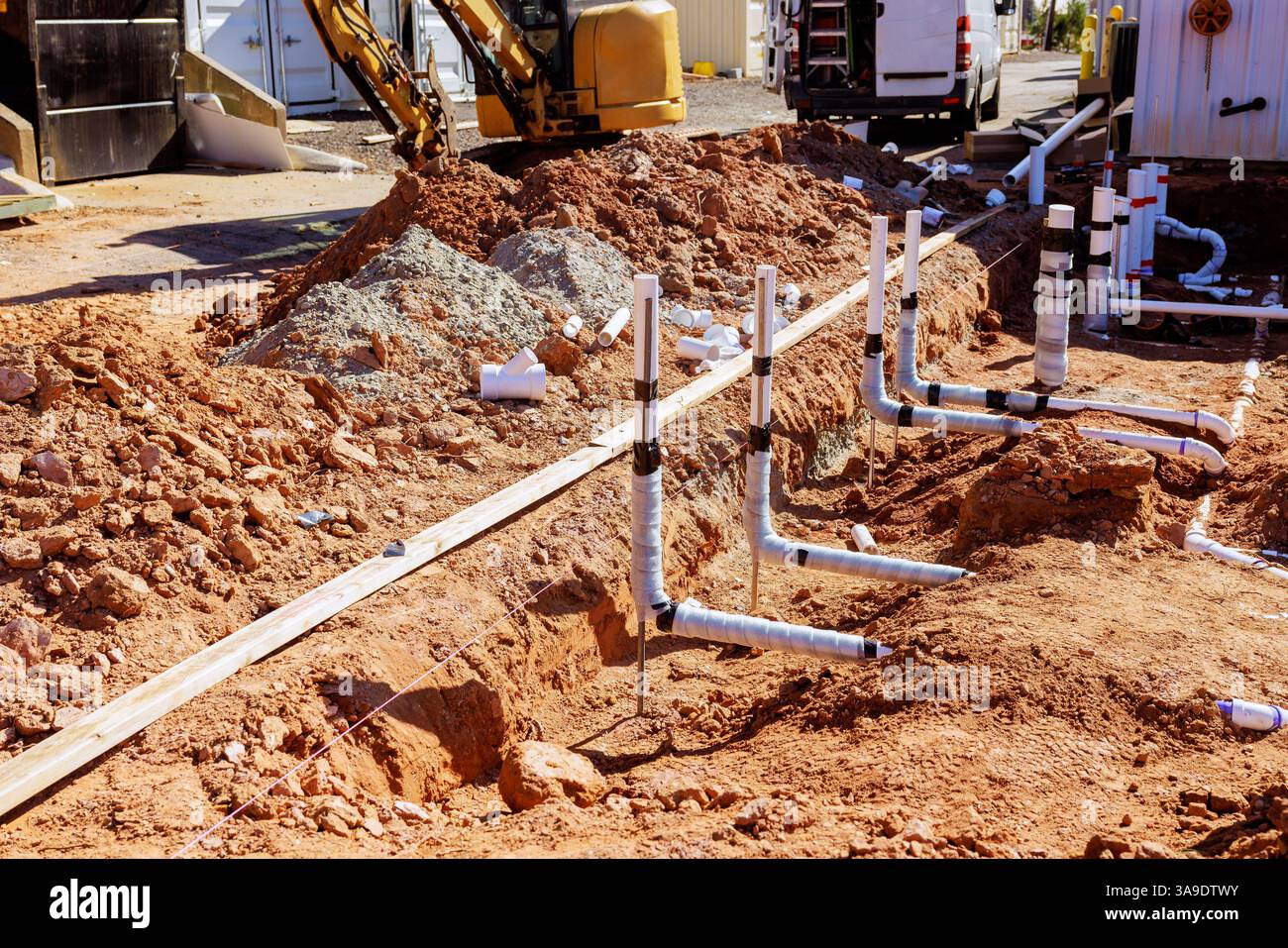 I lavoratori stanno installando tubazioni in pvc per acque reflue in trincee nel cantiere in periferia. Foto Stock