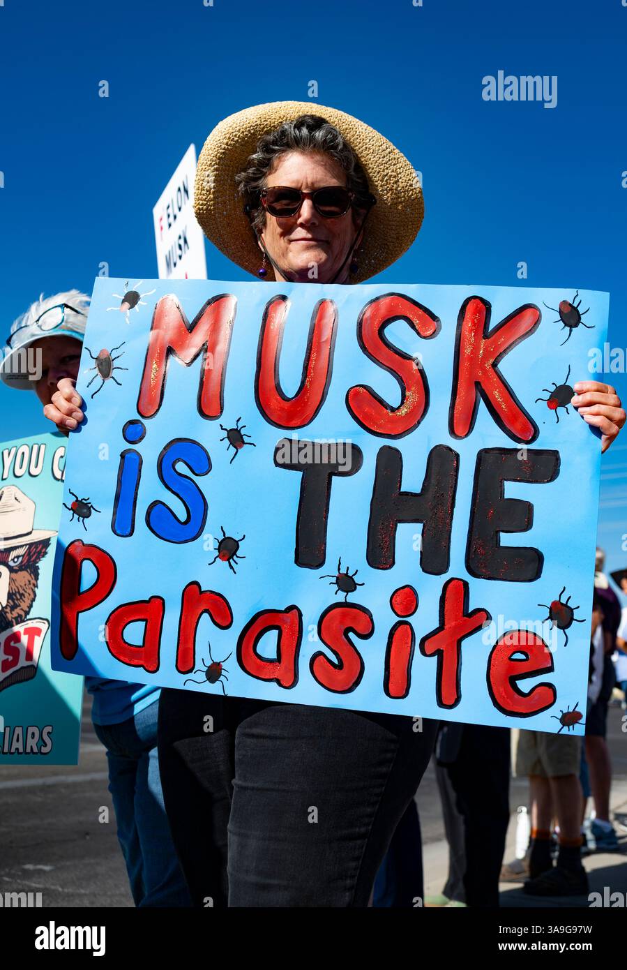 Manifestanti con cartelli che deridono Elon Musk e le buffonate DEL DOGE dell'amministrazione Trump, nonché cartelli con anti-TESLA, presso la concessionaria Tesla di Tucson, Arizona Foto Stock