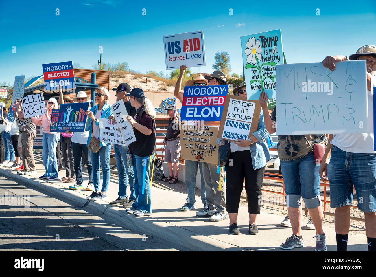 Manifestanti con cartelli che deridono Elon Musk e le buffonate DEL DOGE dell'amministrazione Trump, nonché cartelli con anti-TESLA, presso la concessionaria Tesla di Tucson, Arizona Foto Stock