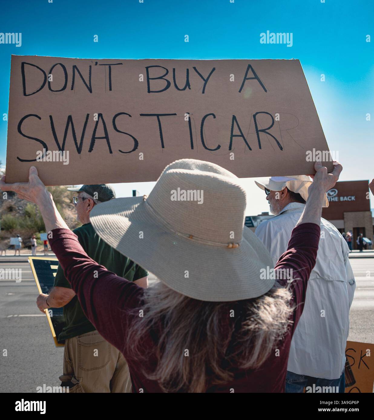 Manifestanti con cartelli che deridono Elon Musk e le buffonate DEL DOGE dell'amministrazione Trump, nonché cartelli con anti-TESLA, presso la concessionaria Tesla di Tucson, Arizona Foto Stock