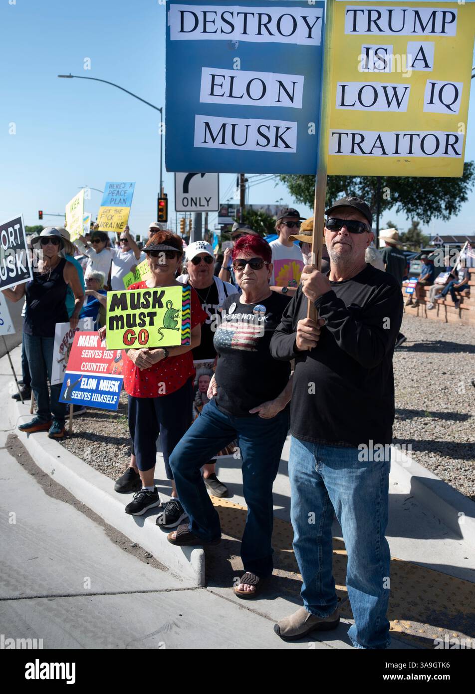Manifestanti con cartelli che deridono Elon Musk e le buffonate DEL DOGE dell'amministrazione Trump, nonché cartelli con anti-TESLA, presso la concessionaria Tesla di Tucson, Arizona Foto Stock