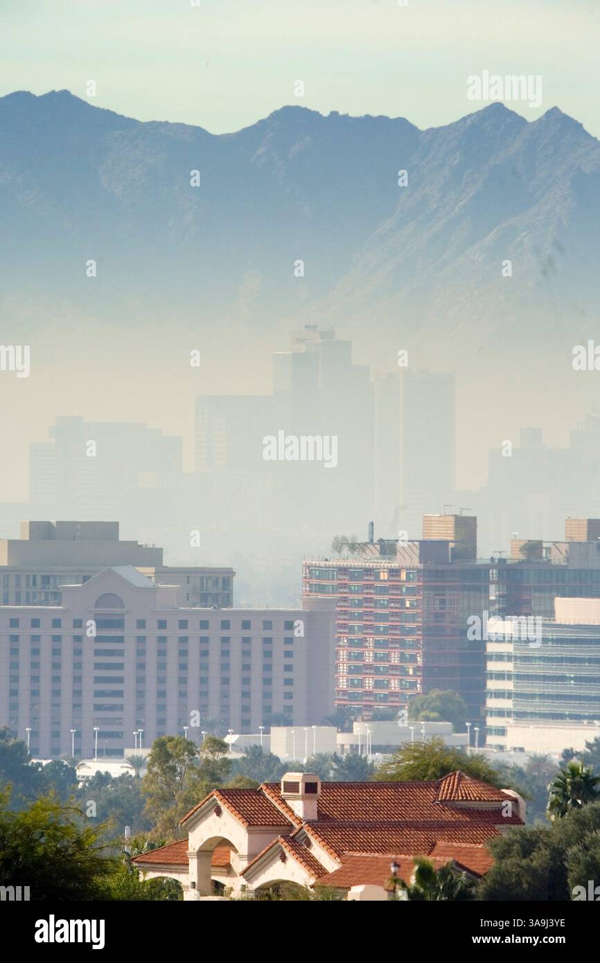 21 dicembre 2005; Phoenix, Arizona, Stati Uniti; la vista del centro cittadino di Phoenix, con sullo sfondo la "South Mountain", è oscurata da alti livelli di inquinamento da particolato. Phoenix, e i suoi sobborghi, lottano con gli elevati livelli di inquinamento da particolato, la "nuvola marrone", ogni inverno. La nuvola marrone è costituita da minuscole particelle di carbonio e biossido di azoto. Queste sostanze si depositano nell'aria principalmente a causa della combustione di combustibili fossili. Automobili, attrezzature per l'edilizia, centrali elettriche, tosaerba, soffiatori di foglie e molto altro ancora contribuiscono alla nuvola, che si forma quando l'inquinamento è intrappolato nell'inversio termico Foto Stock