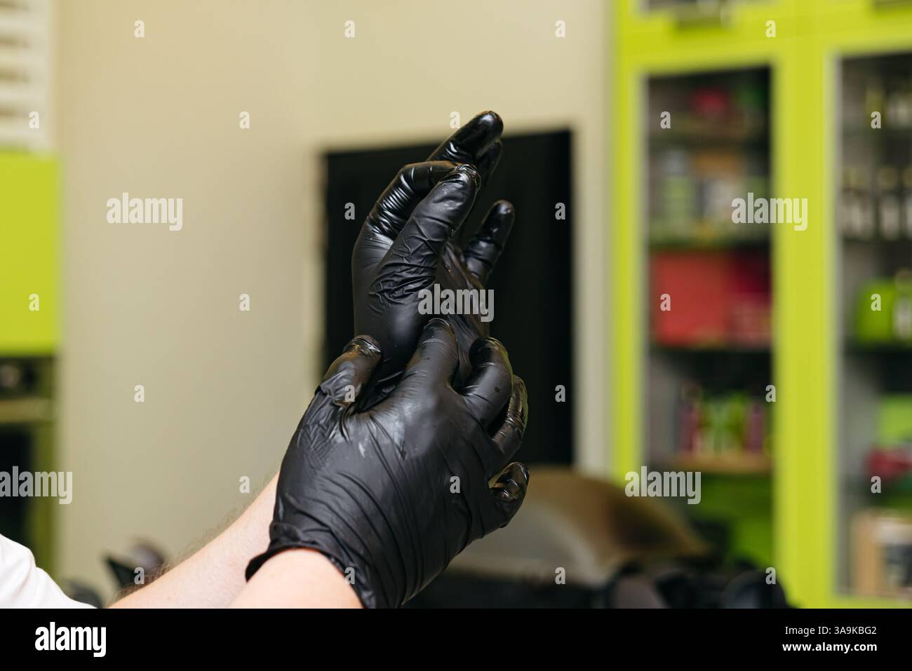 Una persona indossa guanti neri in nitrile in una cucina moderna, evidenziando la pulizia e la sicurezza alimentare prima di cucinare. Foto Stock