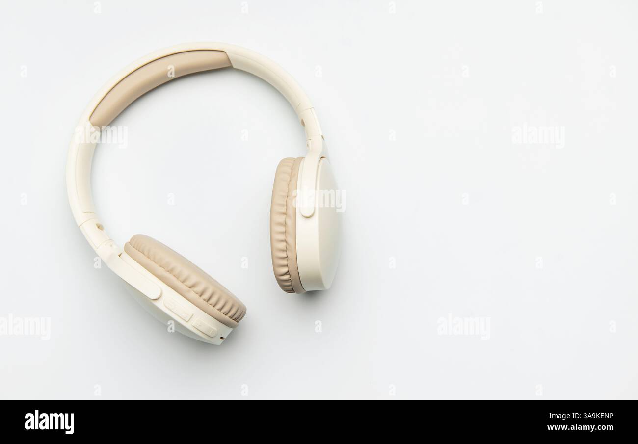 Cuffie wireless beige e bianche isolate su sfondo bianco, che rappresentano l'ascolto di musica, il piacere del podcast o la comunicazione audio Foto Stock
