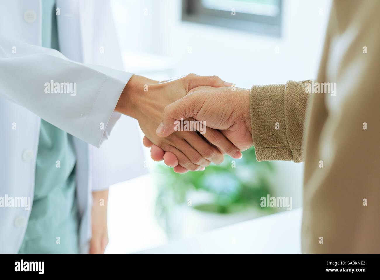 primo piano di un medico e di un paziente anziano che stringono la mano durante una visita in ospedale. Foto Stock