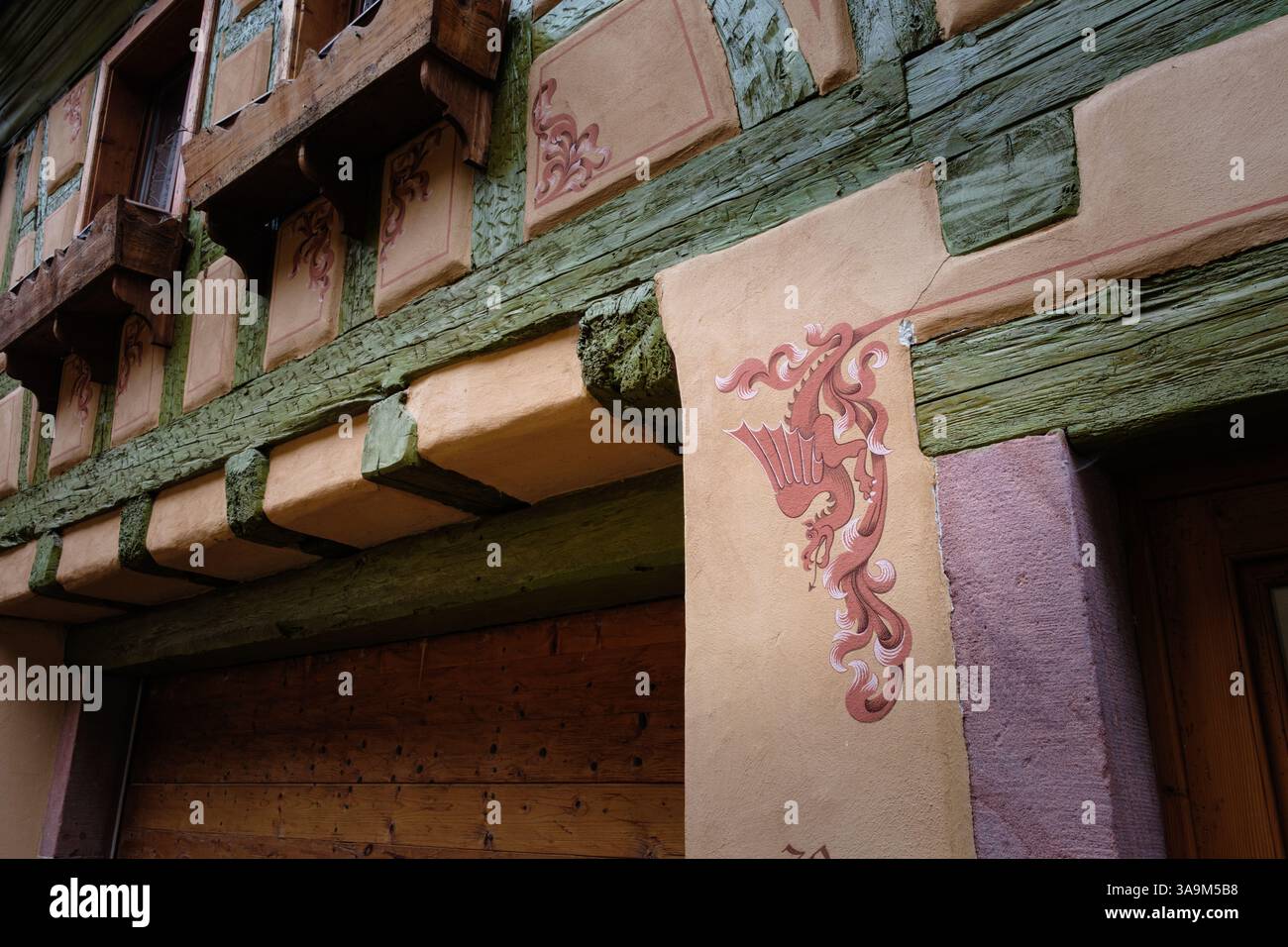 vista orizzontale dell'ingresso di una casa con un drago drwn sul lato della porta, mura medievali per metà in legno Foto Stock