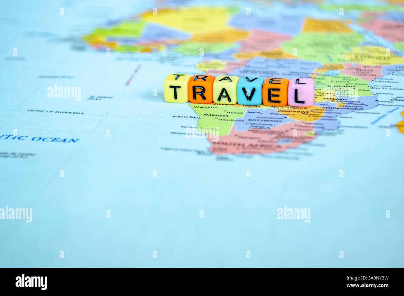 Piccolo cubo di plastica con testo di VIAGGIO posizionato su una mappa del mondo che rappresenta il viaggio o l'esplorazione globale. Foto Stock
