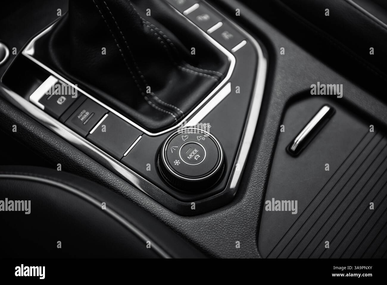 Selettore delle modalità di guida nelle auto moderne. Interni dell'automobile in tonalità scure, vista ravvicinata della parte inferiore della console centrale con selettore del cambio automatico. Foto Stock