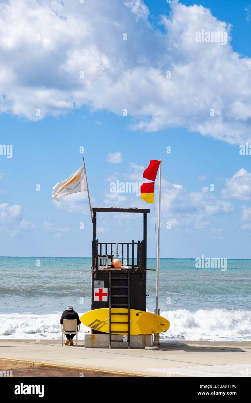 Pathos, Cipro. Una torre bagnino mans su una spiaggia popolare. Venti forti e mari agitati significano che bandiere di avvertimento rosse stanno sventolando per avvisare gli utenti dell'acqua Foto Stock