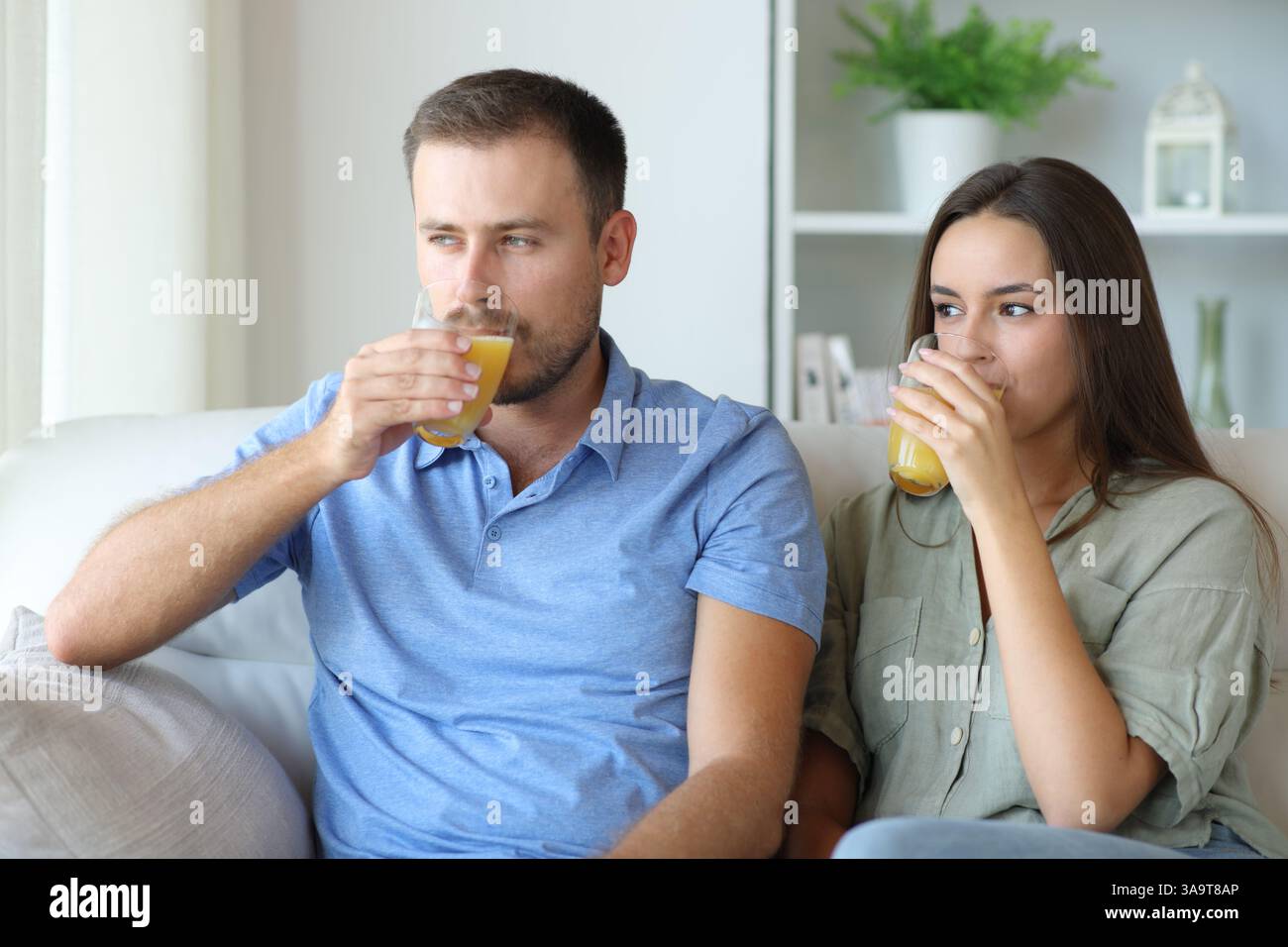 Coppia che beve succo d'arancia seduto su un divano a casa Foto Stock