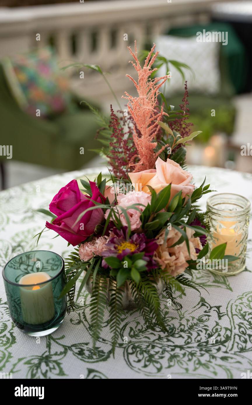 Elegante centro floreale con candele per un romantico matrimonio all'aperto Foto Stock