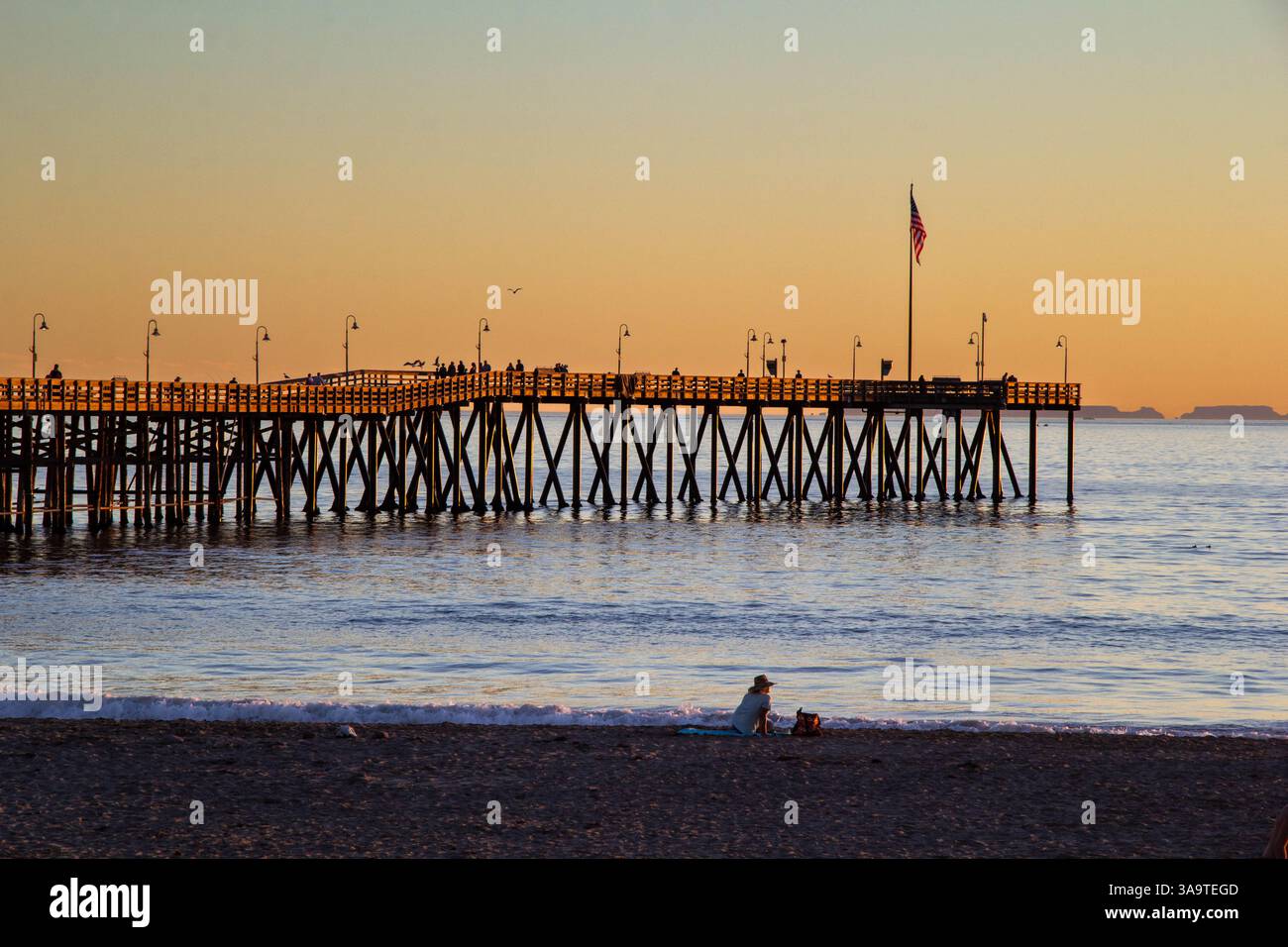 Golden Hour al molo con acque calme e relax sulla spiaggia Foto Stock