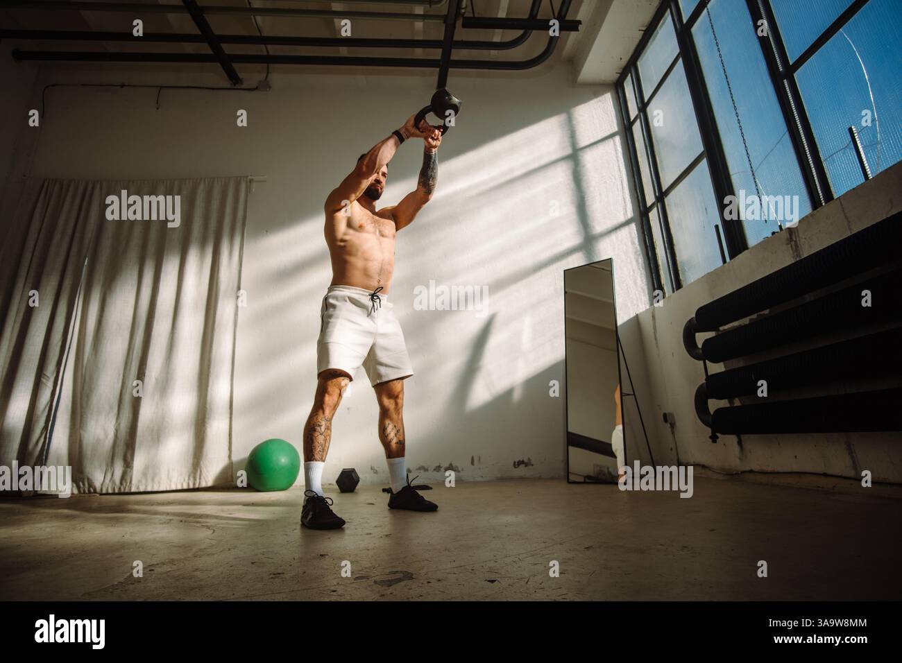 Per risultati ottimali, partecipa a un intenso allenamento a Kettlebell in un moderno ambiente di palestra Foto Stock