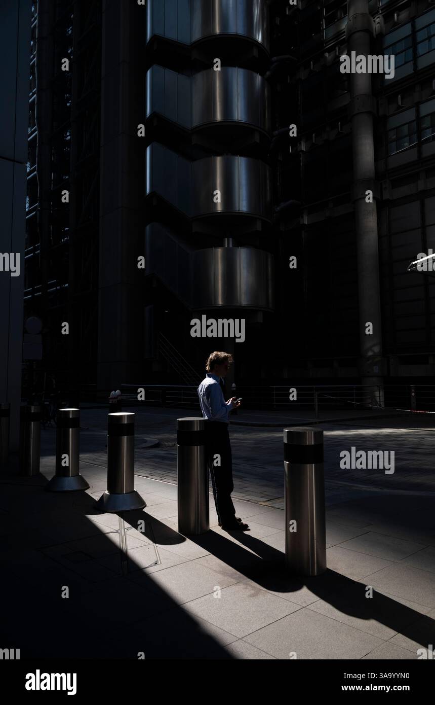 I lavoratori della città si stagliavano per metà alla luce del mattino all'esterno del Lloyds Building in Lime Street, City of London, Inghilterra, Regno Unito Foto Stock