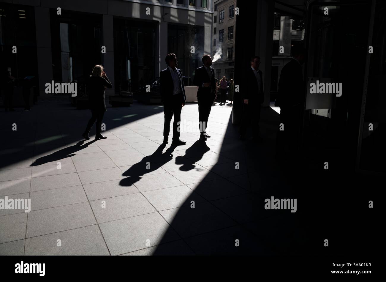 I lavoratori della città si stagliavano per metà alla luce del mattino all'esterno del Lloyds Building in Lime Street, City of London, Inghilterra, Regno Unito Foto Stock